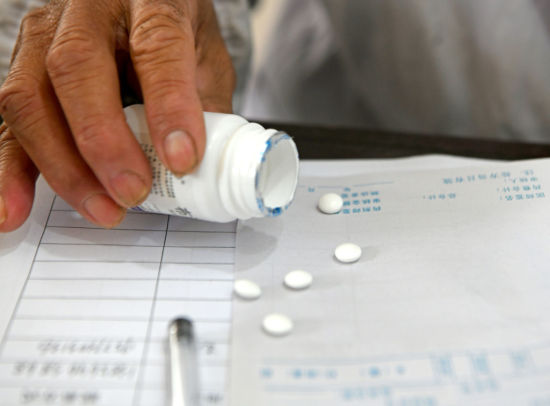 12月21日，安徽淮南的一名村医为发热患者分装退烧药片。